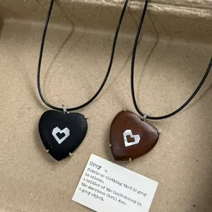 Detailed close-up of two heart-shaped pendant necklaces with geometric inlay on black cords.