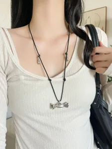 Primo piano dettaglio collana con ciondolo caramella argento e cordino nero chic.