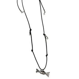 Primo piano dettaglio collana con ciondolo a caramella argento e cordino nero.