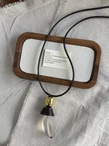 Detailed shot of long black cord necklace with golden bead and frosted teardrop pendant.