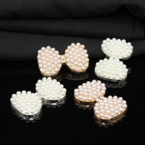 Primo piano di accessori DIY fiocco perla strass per cover cellulare e decorazioni capelli.