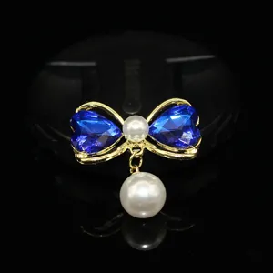 Detailed view of DIY pearl bow jewelry accessory featuring blue crystal hearts and dangling pearl.