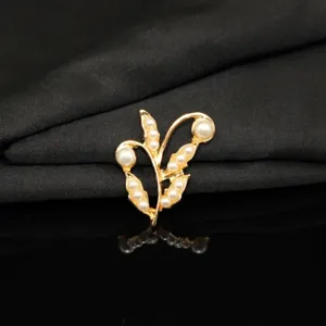 Detailed close-up of gold alloy branch leaf pearl brooch accessory, elegant jewelry texture.