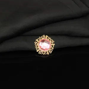 Detailed close-up of a round gold filigree alloy button with pink crystal for DIY crafts.