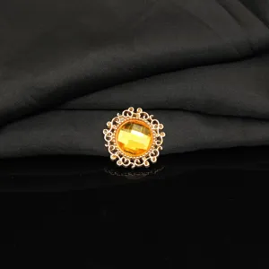 Close-up detail of a golden alloy round rhinestone button with yellow gemstone for DIY craft decor.