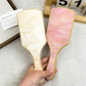 Detail of bamboo paddle hair brushes with elegant pink and cream marble acetate patterns