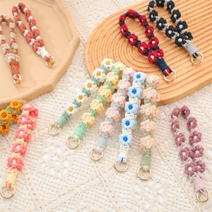 Detalle de correas de mano para llaveros tejidas con flores de margarita de colores