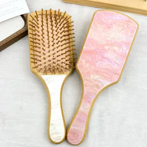 Detailed view of bamboo paddle hairbrushes featuring pink marble acetate patterns
