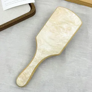 Detailed view of bamboo paddle hairbrush with elegant cream marble acetate finish.
