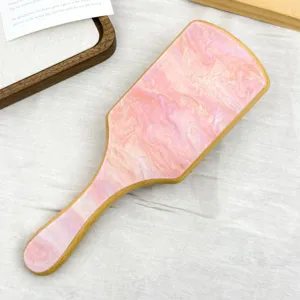 Detailed view of a premium pink marble acetate hairbrush featuring a natural bamboo handle