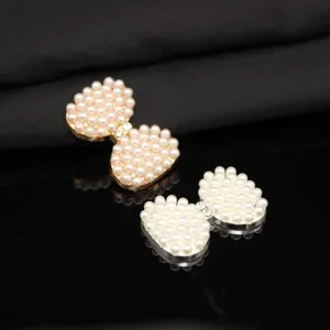 Primo piano accessori fiocco perla DIY, centro strass, base metallo, dettaglio.
