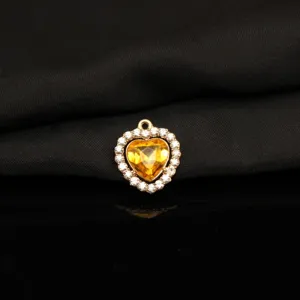 Close-up detail of yellow heart crystal pendant with rhinestones, gold tone alloy jewelry charm.