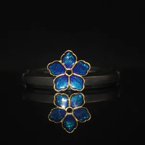 Closeup vibrant blue enamel five-petal flower alloy DIY jewelry accessory component.