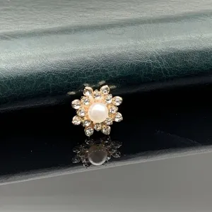 Close-up of a charming rhinestone flower alloy button with a central pearl for DIY craft.