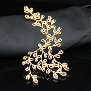 Gros plan détaillé d'une branche de feuille en alliage doré pour accessoire de coiffure de mariée.