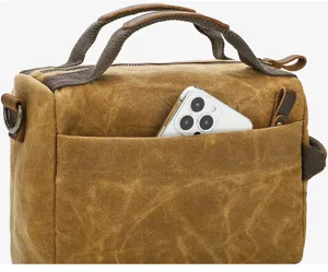 Detail shot of vintage brown waxed canvas shoulder bag front pocket with phone inside.