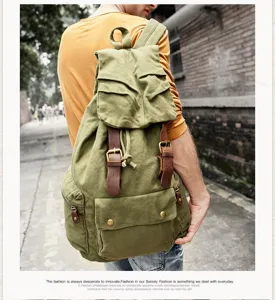 Close-up of vintage canvas backpack with leather straps and multiple pockets in outdoor setting.