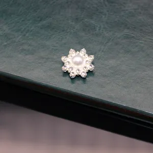 Close-up detail of DIY rhinestone flower alloy charm with central pearl for handmade crafts.