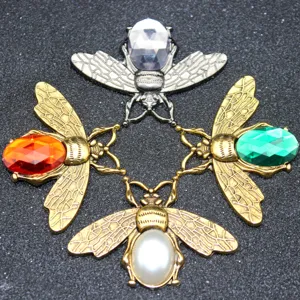 Close-up of decorative bee charms with colorful crystal gemstones and pearl inlay details.