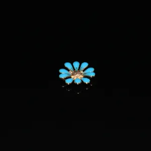Detailed close-up of blue daisy alloy DIY charm with golden center for craft decoration.