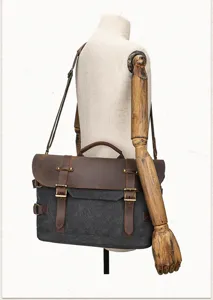 Close up of vintage canvas messenger bag showing metal hardware, durable leather trim, and strap.