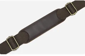 Close-up of durable brown canvas and leather camera bag shoulder strap with bronze metal buckles.