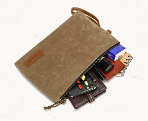 Vintage waxed canvas men's clutch bag detail showing interior storage capacity and zippers.