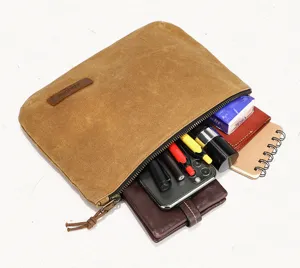 Detail view of brown waxed canvas clutch showing interior storage capacity with daily items.