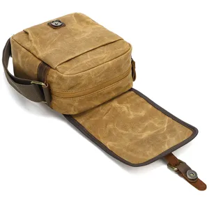 Close-up detail of vintage waxed canvas camera bag opening, showing leather trim and durable hardware.