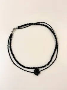 Detailaufnahme der doppelreihigen schwarzen Perlenkette mit Rosenanhänger und Schließe.