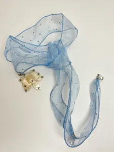 Detailed view of the sheer blue ribbon choker necklace with sparkly rhinestones and a flower.