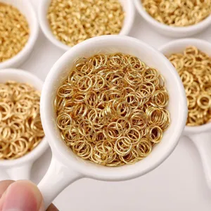 Golden stainless steel open jump rings displayed in white ceramic spoons for DIY handmade jewelry.