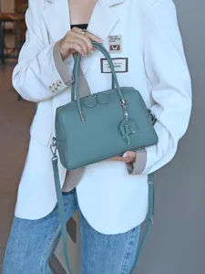 Green leather Boston bag detail, top grain cowhide handbag with crossbody strap and double handles.