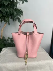 Gros plan sur le sac seau en cuir rose avec détail de cadenas et finitions métalliques.