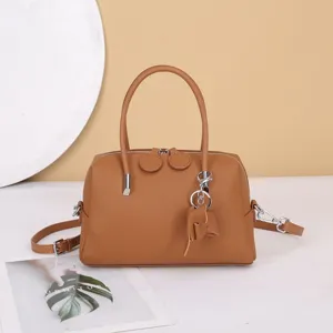 Brown leather boston handbag detail shot, versatile crossbody bag with metal hardware.