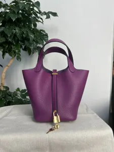 Détail de sac seau en cuir violet montrant une texture premium et un cadenas.