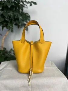 Gros plan détaillé du sac seau en cuir jaune mettant en valeur le grain et son fermoir.