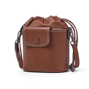 Brown leather bucket bag with drawstring closure, front pocket and adjustable strap for women.