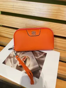 Orange leather clutch wallet for women, top layer cowhide wristlet bag with chic clover metal decor.