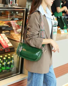 Green genuine leather pillow shoulder bag with wide strap, detailed lifestyle shot.