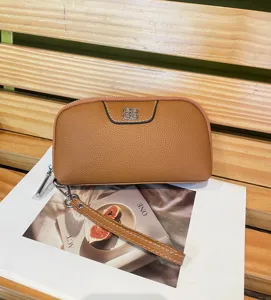 Brown genuine leather clutch wallet detail, featuring a delicate silver clover metal accent.