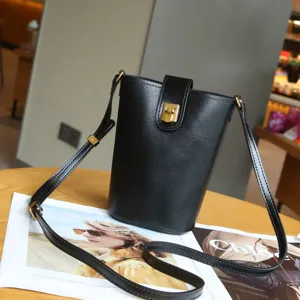 Black genuine leather bucket bag with metal lock closure and adjustable strap for women.