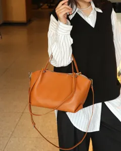 Detail view of the stylish brown leather tote bag with handles and a crossbody strap.