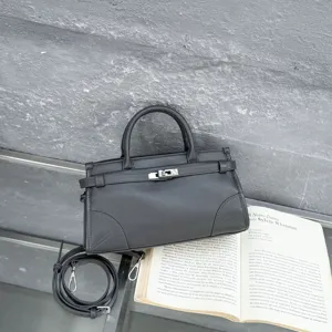 Dark grey leather handbag detail showcasing classic top handle and metal lock design.