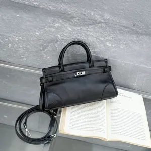Black leather handbag detail view, retro top handle bag with metal lock and shoulder strap.