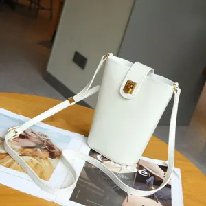 White leather vertical phone bag detail shot, minimalist cross body shoulder bag with metal lock.