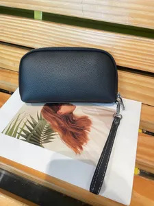 Detailed view of a black textured leather wristlet clutch bag showcasing fine craftsmanship.