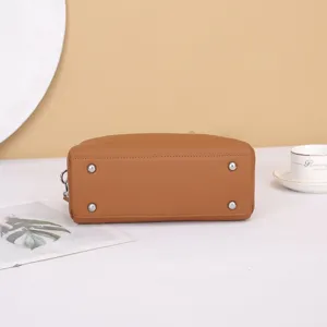 Detailed bottom view of brown leather Boston handbag featuring protective metal feet.