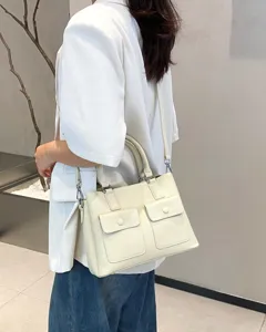 Detail view of a stylish genuine leather tote bag in beige with double front pockets.