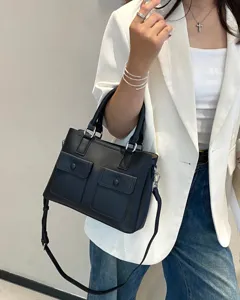 Detail view of black genuine leather tote bag with double front pockets and crossbody strap.
